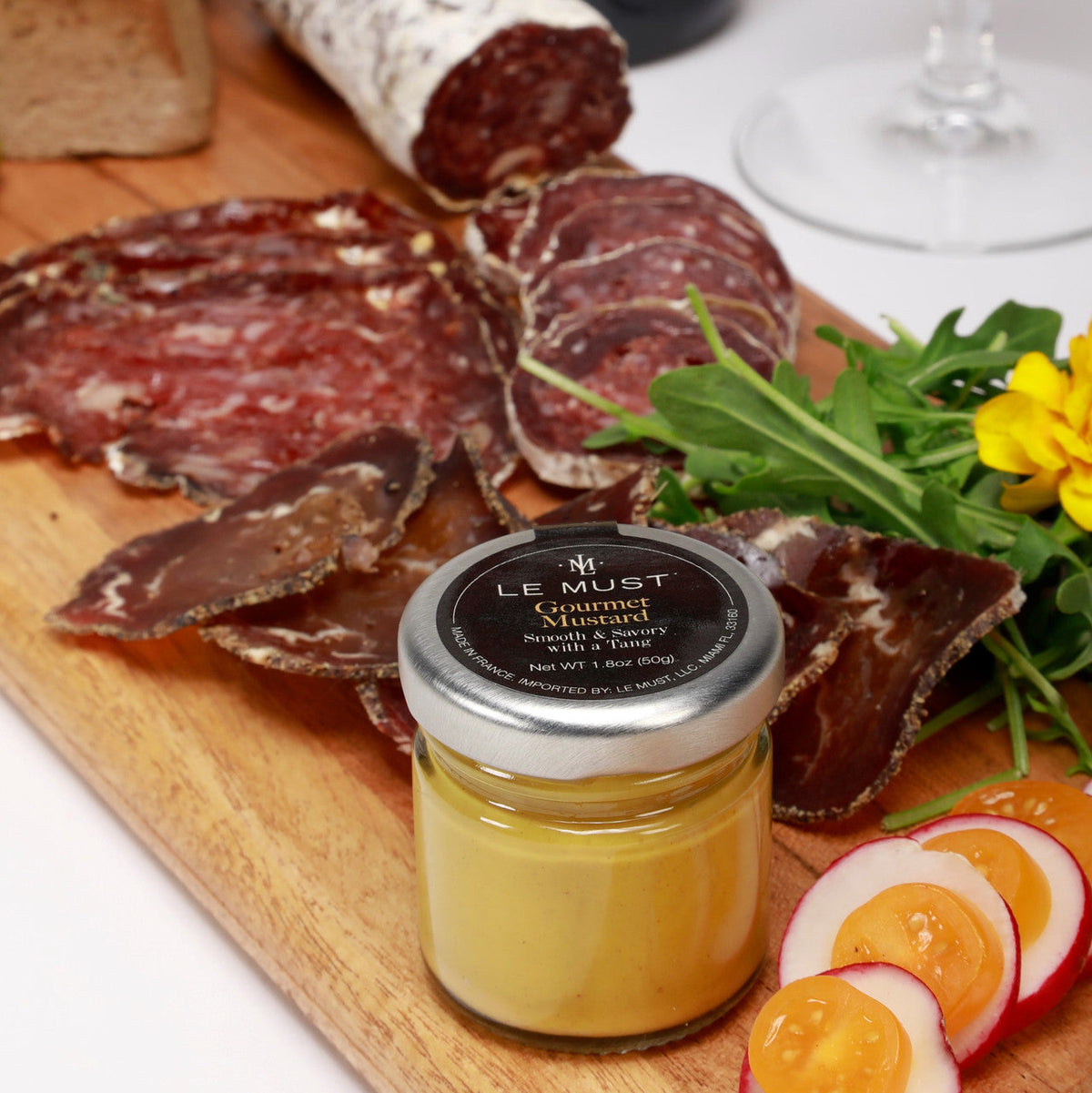 Le Must Premium Organic Dijon Mustard, 33 grams, on a charcuterie board